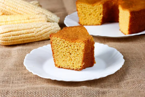 corn cake on white plate on rustic wooden table. Typical Brazilian party food. Selective focus