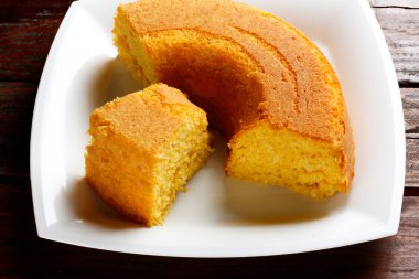 Beyaz tabakta hindistan cevizli mısır keki ve ahşap masa. Tipik Brezilya parti yemekleri. Seçici odak