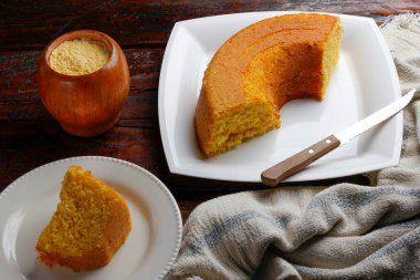 Beyaz tabakta hindistan cevizli mısır keki ve ahşap masa. Tipik Brezilya parti yemekleri. Seçici odak