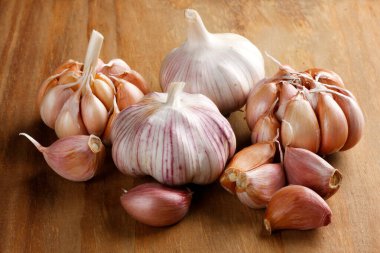 Raw 'ı kapatın, sarımsaklı karanfiller ve ahşap masa üzerindeki ampuller. Ön görünüm