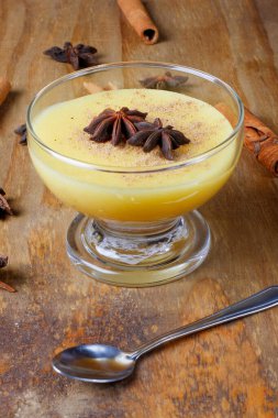 Curau, mısır tatlısı kreması ve Brezilya mutfağının tipik bir çeşidi. Tahta masadaki cam kaseye konmuş. Kapat.