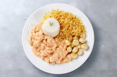 Çimento masasında izole edilmiş seramik tabakta ev yapımı tavuk stroganoff. Üst Görünüm