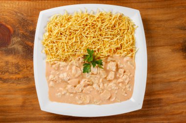 Ahşap masaya izole edilmiş seramik tabakta ev yapımı tavuk stroganoff. Üst Görünüm