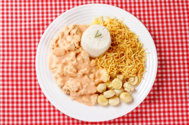 Kırmızı kareli masa örtüsü üzerinde seramik tabakta ev yapımı tavuk stroganoff. Üst Görünüm