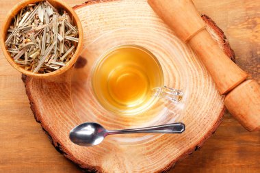 Kırsal ağaç gövdesinde cam bardakta limon otu çayı. Görüntüyü kapat