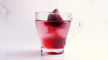 Tea bag infused in water for a hot tea. Making a tea in a transparent cup. Healthy drinking concept. Slow motion