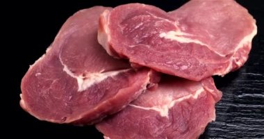Siyah taşın üzerinde dönen çiğ et parçaları. Sağlıklı bir diyete hazır taze et. Et kaynağı protein. Dolly 4K çekti.