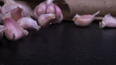 Fresh garlic clove falling on black background. The raw garlic is one of the most popular ingredients of the basic recipes with nutritional properties, infamous aroma and health benefits. Slow motion