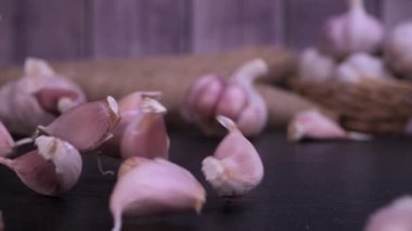 Fresh garlic clove falling on black background. The raw garlic is one of the most popular ingredients of the basic recipes with nutritional properties, infamous aroma and health benefits. Slow motion