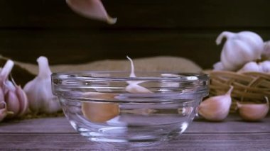 Cam kaseye düşen taze sarımsak. Çiğ sarımsak besin özellikleri, kötü şöhretli aroma ve sağlık yararları ile temel tariflerin en popüler bileşenlerinden biridir. Yavaş çekim