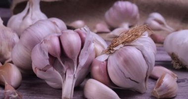 Fresh garlic with intense unique flavor and aroma on wooden background. One of the most popular ingredients of the basic recipes with nutritional properties and health benefits. Dolly shot 4k