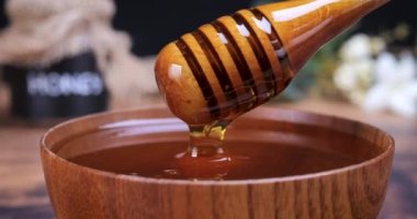Honey spoon coming out of the bowl full of honey. Honey contains many nutrients, antioxidants, improves heart health, wound care, offers antidepressant and anti-anxiety benefits. 4k
