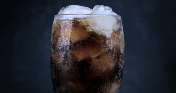 氷と泡とクールなコーラの飲み物 新鮮な冷たい甘い飲み物が氷のキューブの上に注がれました ブラックに夏のリフレッシュを施したコーラグラス 4Kについて — ストック動画