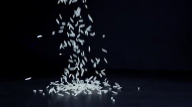Basmati beyaz pirinci siyah arka planda ağır çekimde düşüyor. Basmati pilavı güzel kokulu, lezzetli uzun taneli beyaz pirinçtir. Sağlıklı gıda konsepti.