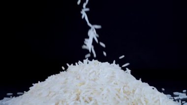 Basmati beyaz pirinci siyah arka planda ağır çekimde düşüyor. Basmati pilavı güzel kokulu, lezzetli uzun taneli beyaz pirinçtir. Sağlıklı gıda konsepti.