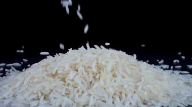 Basmati beyaz pirinci siyah arka planda ağır çekimde düşüyor. Basmati pilavı güzel kokulu, lezzetli uzun taneli beyaz pirinçtir. Sağlıklı gıda konsepti.
