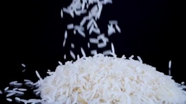 Basmati beyaz pirinci siyah dönen arka planda yavaş çekimde düşüyor. Basmati pilavı güzel kokulu, lezzetli uzun taneli beyaz pirinçtir. Sağlıklı gıda konsepti.
