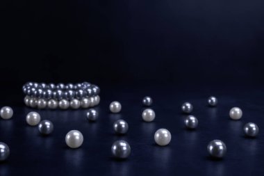 Siyah arka planda beyaz ve gri inci ve bilezikler. Moda, aksesuar, mücevher, lüks, zenginlik konsepti.