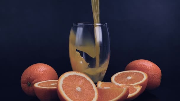 Φρέσκος Χυμός Πορτοκαλιού Χυμένος Ποτήρι Μαύρο Φόντο Χυμός Πορτοκαλιού Περιέχει — Αρχείο Βίντεο