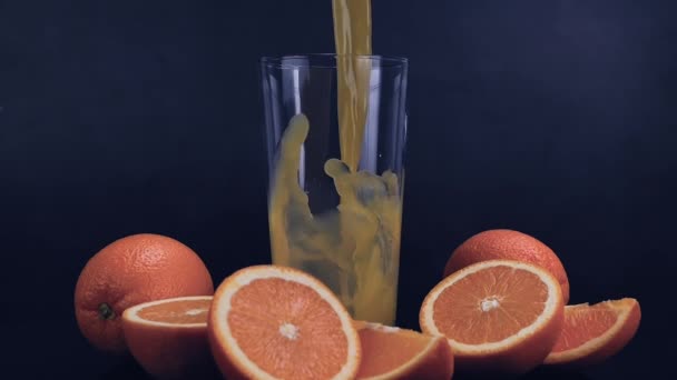 Φρέσκος Χυμός Πορτοκαλιού Χυμένος Στο Ποτήρι Μαύρο Φόντο Χυμός Πορτοκαλιού — Αρχείο Βίντεο