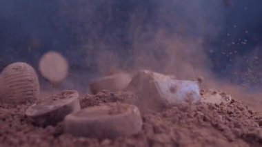 Çikolatalı pralinler siyah arka planda kakao tozuna dökülüyor. Şeker konsepti tüketimi. Yavaş çekim