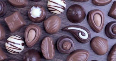 Kahverengi arka planda sütlü ve koyu çikolatalı pralinler. Çikolata ve tatlı tüketim konseptini sevmek. Dolly 4K çekti.