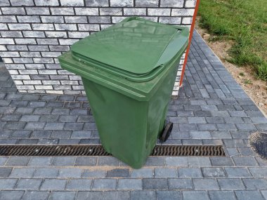 Modern evin önünde bireysel kullanım için boş yeşil plastik çöp kutusu