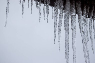 Bir konağın çatısında büyük buz sarkıtları. Evin çatısı kışın buz saçaklarıyla kaplı.