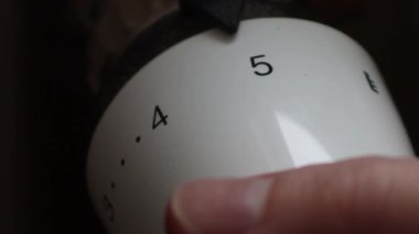 Close up hand adjusting heating temperature. Reducing heating cost in crisis. War in Ukraine. Energy crisis. regulating temperature knob concept