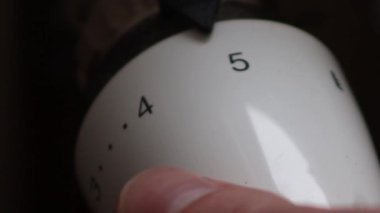 Close up hand adjusting heating temperature. Reducing heating cost in crisis. War in Ukraine. Energy crisis. regulating temperature knob concept