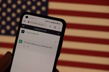Warsaw Poland - February 24, 2023:  prototype AI chatbot, seen on the website of OpenAI - smartphone.  new wave of chatbots like ChatGPT use AI with USA flag
