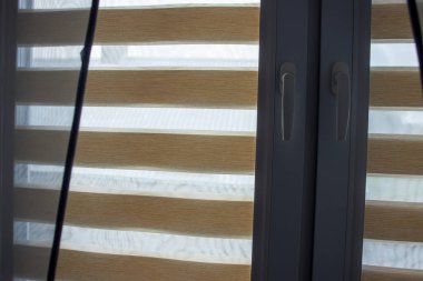 Şık bir gece-gündüz panjurları güzel aydınlatılmış bir oda penceresini süslüyor.