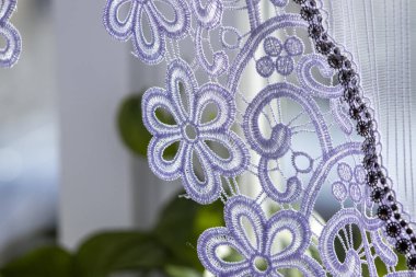 Beyaz çiçek desenli perdelerin yakın çekimi samimi bir evin içinde.