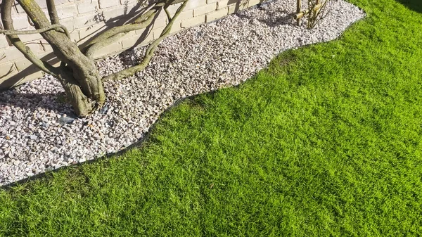 Lush green lawn with an edging of small garden stones