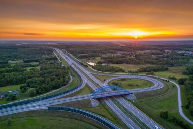 Otoyol köprüsünün havadan görünüşü ve ufukta gün batımı. Seyahat ulaşımı, yol ve otoyol inşaatı kavramı