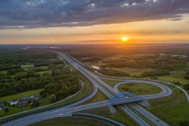 Otoyol köprüsünün havadan görünüşü ve ufukta gün batımı. Seyahat ulaşımı, yol ve otoyol inşaatı kavramı
