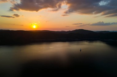 Gün batımında güzel bir göl manzarası. Gün batımı gölün üzerinde uzak dağ silueti ile görülür..