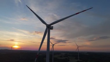 Gün batımında rüzgâr türbinleri çiftliğinin manzarası. Rüzgar türbini alternatif enerji üretiyor