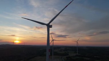 Gün batımında rüzgâr türbinleri çiftliğinin manzarası. Rüzgar türbini alternatif enerji üretiyor