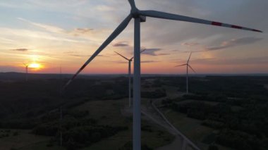 Gün batımında rüzgâr türbinleri çiftliğinin manzarası. Rüzgar türbini alternatif enerji üretiyor
