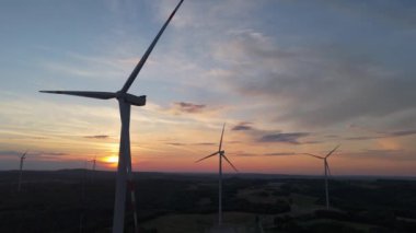 Gün batımında rüzgâr türbinleri çiftliğinin manzarası. Rüzgar türbini alternatif enerji üretiyor