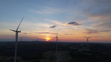 Gün batımında rüzgâr türbinleri çiftliğinin manzarası. Rüzgar türbini alternatif enerji üretiyor