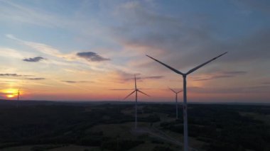 Gün batımında rüzgâr türbinleri çiftliğinin manzarası. Rüzgar türbini alternatif enerji üretiyor