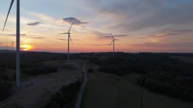 Gün batımında rüzgâr türbinleri çiftliğinin manzarası. Rüzgar türbini alternatif enerji üretiyor
