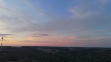Gün batımında rüzgâr türbinleri çiftliğinin manzarası. Rüzgar türbini alternatif enerji üretiyor