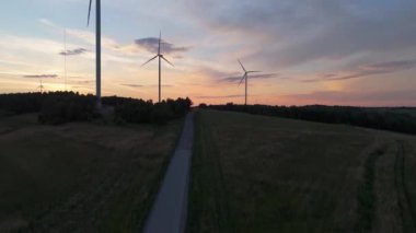 Gün batımında rüzgâr türbinleri çiftliğinin manzarası. Rüzgar türbini alternatif enerji üretiyor