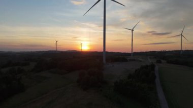 Gün batımında rüzgâr türbinleri çiftliğinin manzarası. Rüzgar türbini alternatif enerji üretiyor