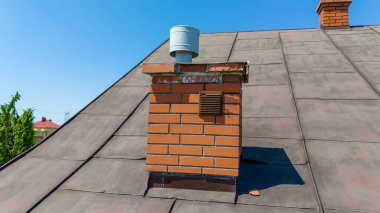 A close-up of a brick chimney on a roof against a clear blue sky. Perfect for home improvement, construction, and architecture themes. clipart