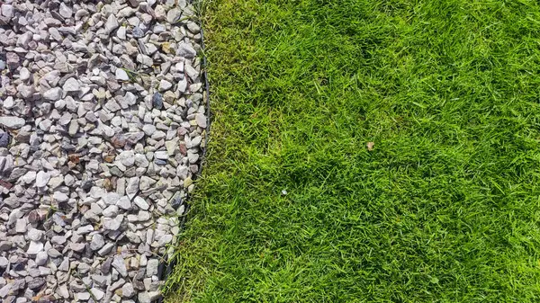 Canlı ve zıt bir tasarım. Dekoratif çakıl taşlarının yanında yemyeşil çimenler var. Peyzaj, bahçıvanlık ya da açık hava temaları için ideal..