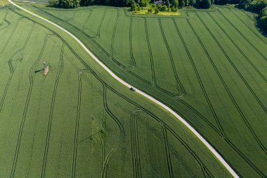 Bereketli yeşil çayırlarda dolambaçlı bir yolun havadan görünüşü, canlı kırsal bölgeleri gösteriyor. Doğa aşıkları ve doğa tutkunları için mükemmel..